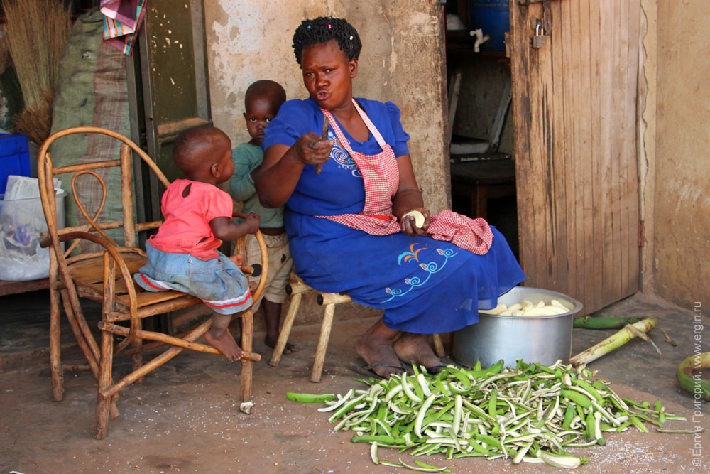 Черная женщина чистит зеленые бананы деревня Назиго Уганда