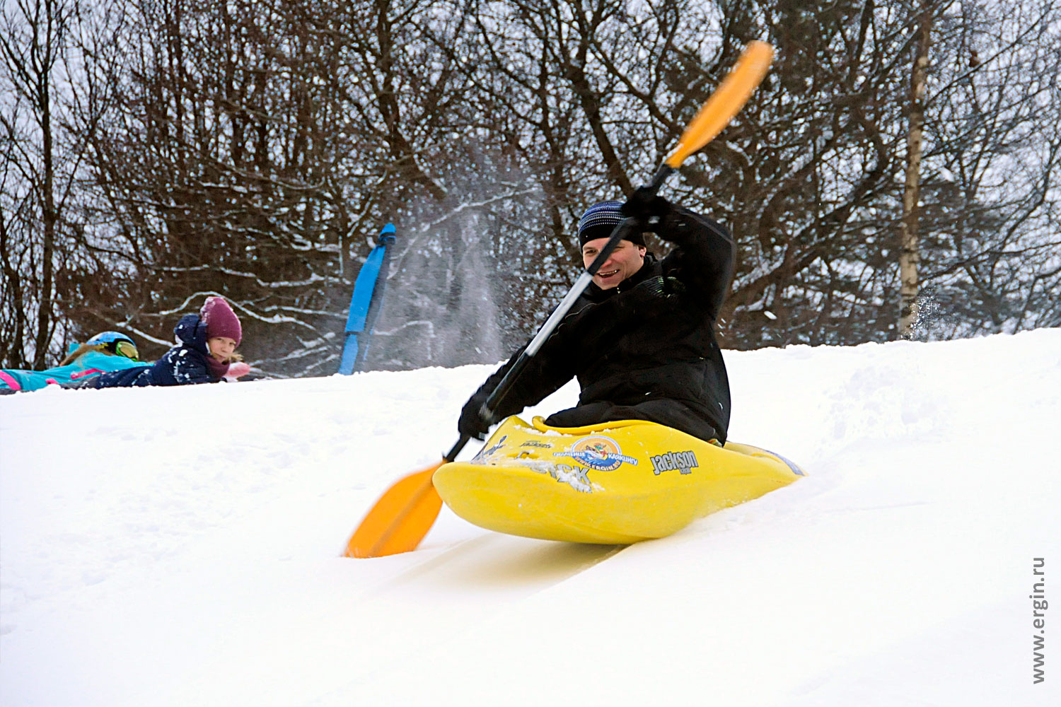 Сноукаякер едет на каяке по снегу и радуется занимается сноукаякингом